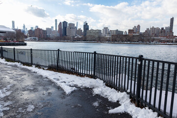 East River Riverfront in Astoria Queens New York Covered with Snow during the Winter with a View of the Roosevelt Island and Manhattan Skyline
