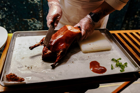 Chinese cook prepares Peking Roast Duck. Peking Duck is a famous duck dish from Beijing that has been prepared since the imperial era, and is now considered one of China's national foods.