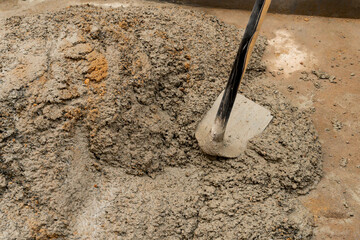 Indian labour mixing cement and water manually on floor using a shovel. Stock image.