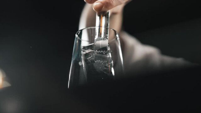 Professional bartender is putting ice in a beautiful glass