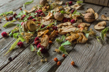 Dried delicious delicacies. Dry pieces of linden, rose hips, pears, raspberries, apples and walnuts snack on a wooden background