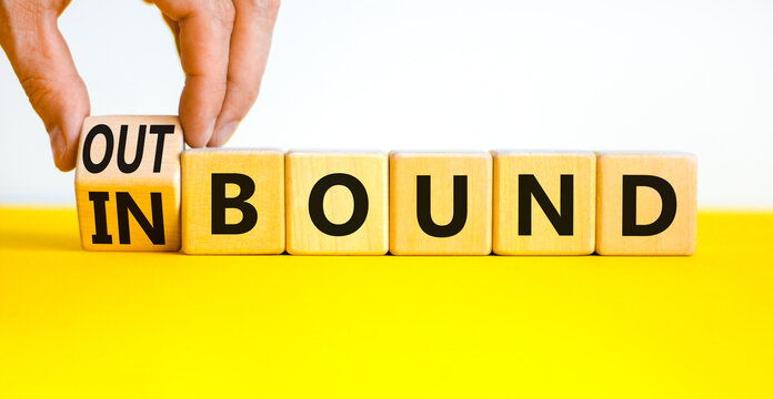 Inbound or outbound symbol. Businessman turns wooden cubes and changes the concept word Outbound to Inbound. Beautiful yellow table white background. Business inbound or outbound concept. Copy space.