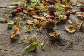 Dried delicious delicacies. Dry pieces of linden, rose hips, pears, raspberries, apples and walnuts snack on a wooden background