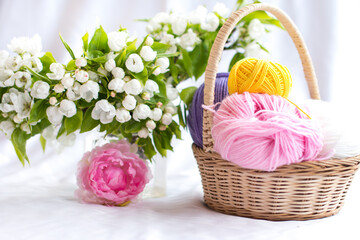 a wicker basket with yarn under a blooming apple tree. Nature and needlework, knitting