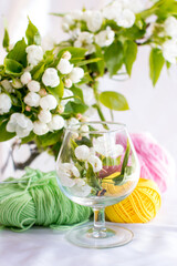 a wicker basket with yarn under a blooming apple tree. Nature and needlework, knitting
