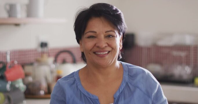 Portrait of smiling senior biracial woman in kitchen alone