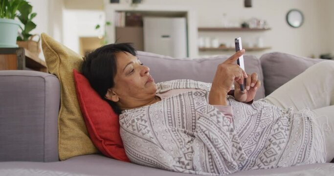African american senior woman using digital tablet lying on the couch at home