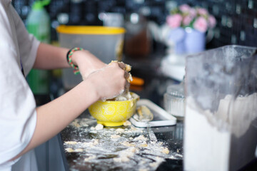 The girl's hands make dough in the kitchen at home