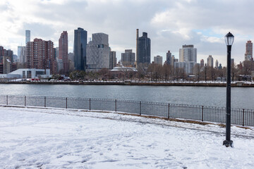 Roosevelt Island and Manhattan Skyline along the East River seen from Rainey Park covered in Snow...