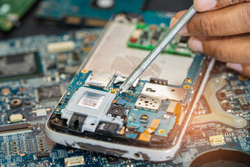 Technician repairing inside of mobile phone by soldering iron. Integrated Circuit. the concept of...