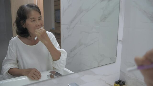 Health concept of 4k Resolution. Asian old woman brushing teeth in the bathroom.