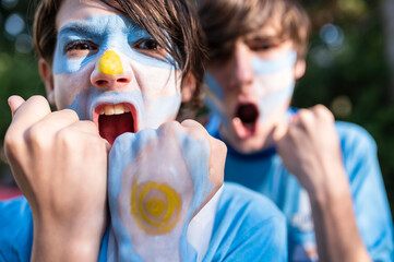 Friends soccer fans painted with the colors of the Argentine team celebrating the goals.