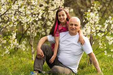 happy granddaughter hugging her smiling grandfather on green lawn