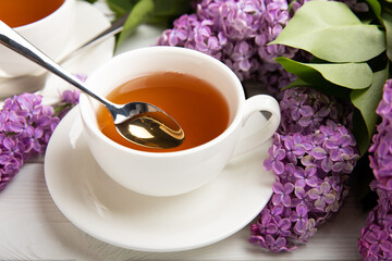 A cup of green tea against the background of a spring bouquet of lilacs on a textured gray background.Romantic composition with books and candles. Spring tea drink. Place to copy.