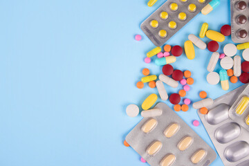Variety of medicine pills, capsules and tablets in blisters on blue background with copy space for your text. Immune system vitamins and supplemets. Dietary bio supplements. Selective focus