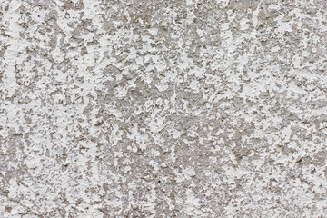 An old concrete wall with remnants of gray paint crumbling from time. Texture of eroded concrete.