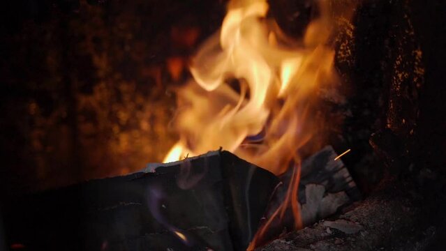Fire from firewood burns in the firebox of a solid fuel water boiler close-up