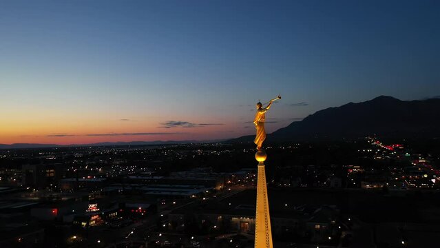 LDS Mormon Temple, angle Moroni on golden spire. Night drone orbit 4k