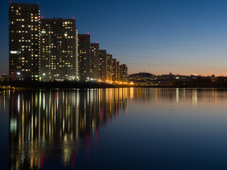 Night city. Houses are reflected in the water. Siberian city of Krasnoyarsk