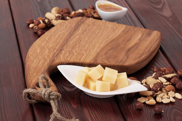 Cheese cut into pieces on a wooden board. Serving cheeses with honey and nuts.