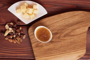 Cheese cut into pieces on a wooden board. Serving cheeses with honey and nuts.