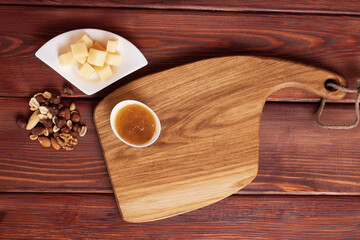 Cheese cut into pieces on a wooden board. Serving cheeses with honey and nuts.