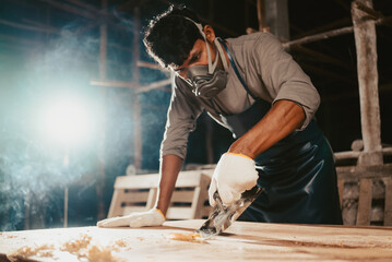 Confident wood worker expert. Young man working at factory. Skilled carpenter cutting a piece of...