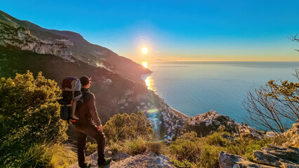 Active man with backpack watching sunrise from hiking trail Path of Gods between Positano and...