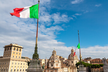 Italian national flag moving in wind with view on dome of Santa Maria di Loreto church and dome of...