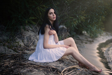 Beautiful sexy girl in a short white dress in nature near the river