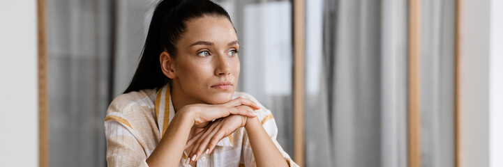 White brunette woman reading book while having breakfast at home