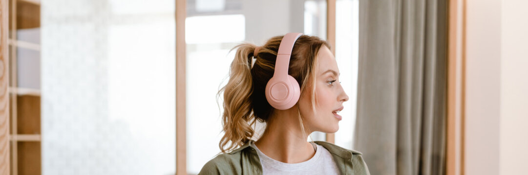 Young woman listening music with cellphone and headphones at home