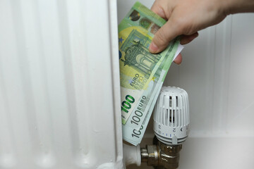 temperature regulation in the house with a thermostat on the white radiator, 100 euro banknotes,...