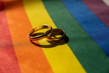 Legalization of same-sex marriages. Rainbow flag and wedding rings.