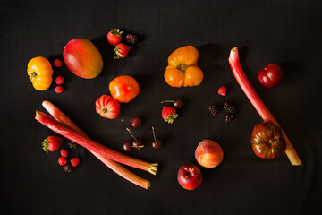 red fruit still life with heirloom tomatoes, blackberries, strawberries, cherries, raspberries, and rhubarb