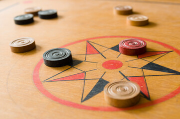 A game of carrom with scattered stones on the board around the center star - obrazy, fototapety, plakaty