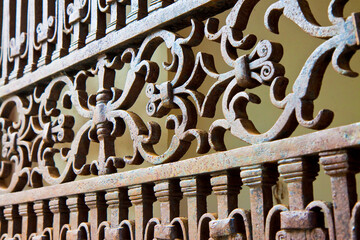 Detail of an old rusty cast iron gate with floral decoration