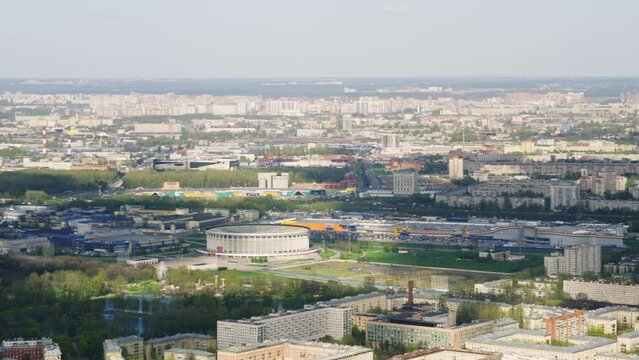 A view from a helicopter flying over an urban area with a round large stadium of the Skk in St. Petersburg. Flying past cityscape of Soviet architecture. A bird's-eye view of city landscape. 