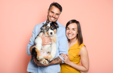 Handsome couple with her Australian Berger puppy on studio pink color