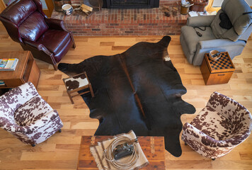 Furniture arrangement in living room with ranch cowboy western theme. Cowhide rug is near brick fireplace. Overhead view of central part of great room includes wood floor, cedar chest and horse statue - obrazy, fototapety, plakaty