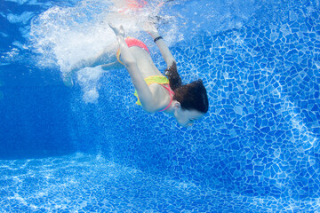 Young girl jumps in the pool. Underwater image.
