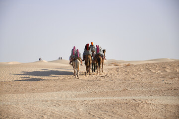 Karawana wielbłądów z turystami na pustyni. - obrazy, fototapety, plakaty