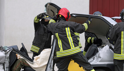 after the road accident the firefighters remove the hood from the car to free the injured person...
