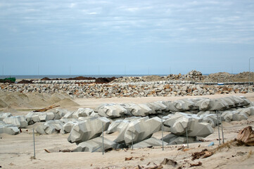 Plac budowy plaża materiały budowlane betonowe bloczki i stalowe pręty zwały piasku.	
