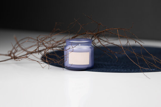 
purple candle with aroma in glass against the background of branches. Place for your advertising and inscriptions