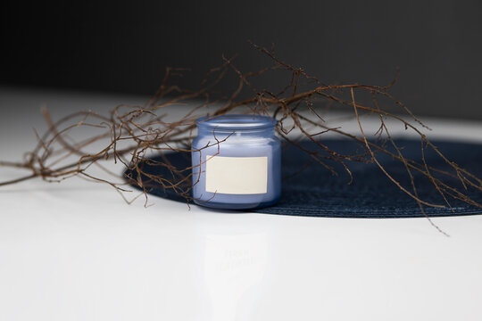 
purple candle with aroma in glass against the background of branches. Place for your advertising and inscriptions