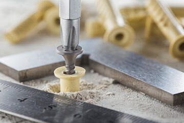 screwdriver screw and dowel in a concrete wall background