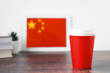 National flag of China on the tablet, textbooks, a red cup of hot drink coffee or tea on the table, the concept of learning Chinese