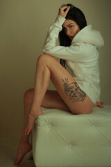 beautiful fashionable brunette girl with tattoos posing in studio