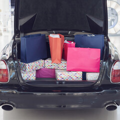 A car with an open trunk is filled with shopping bags. Advertising installation in a shopping...